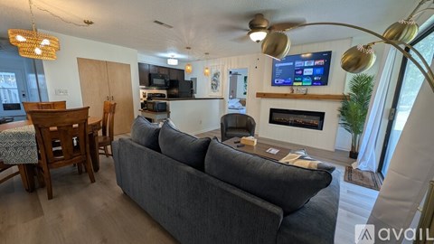 A living room with a grey couch and a television mounted on the wall.