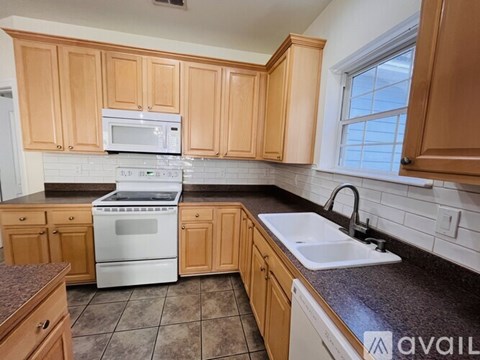 A kitchen with wooden cabinets and a white stove top oven.