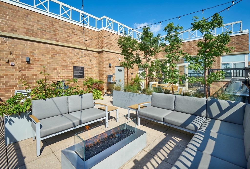A patio with grey couches and a fire pit.