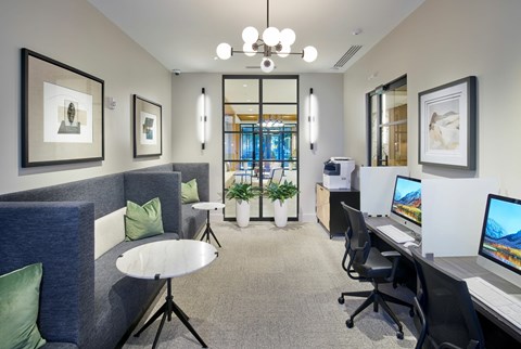 A modern office space with a blue couch, desks, and computers.