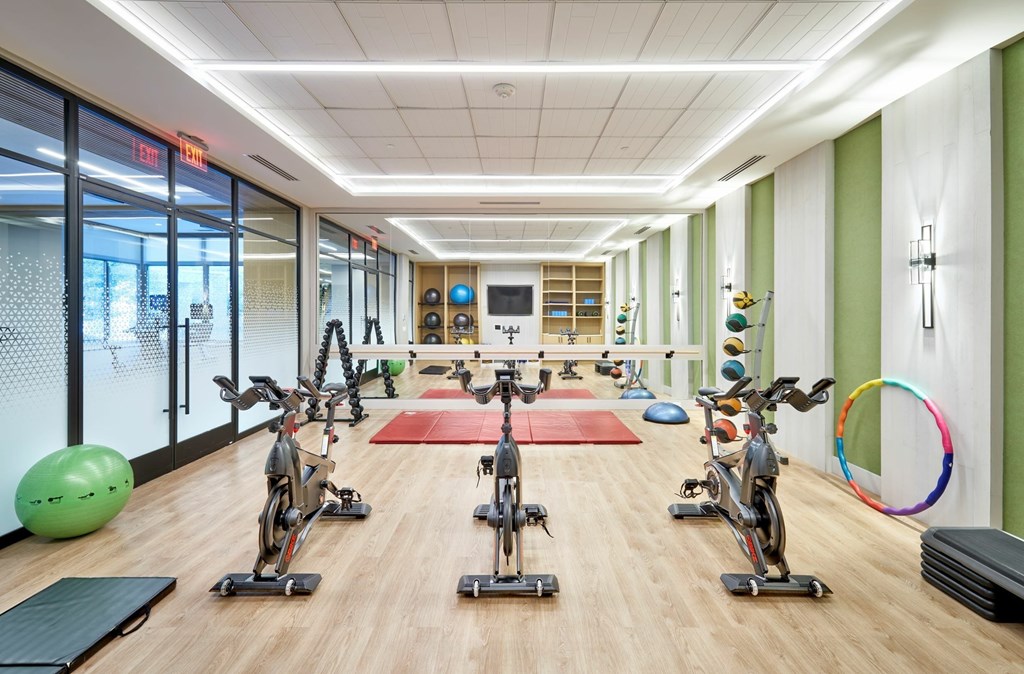 A gym with exercise bikes and a green exercise ball.