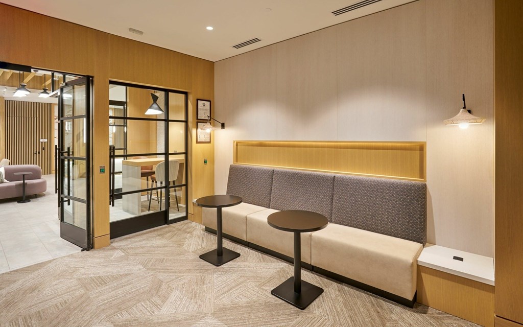 A modern waiting area with a bench, table, and a glass door.