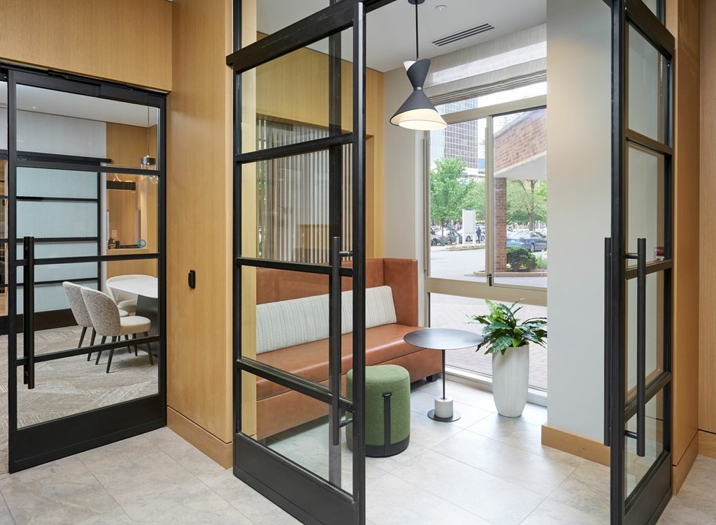 A glass door with a black frame is open to a room with a couch and a table.