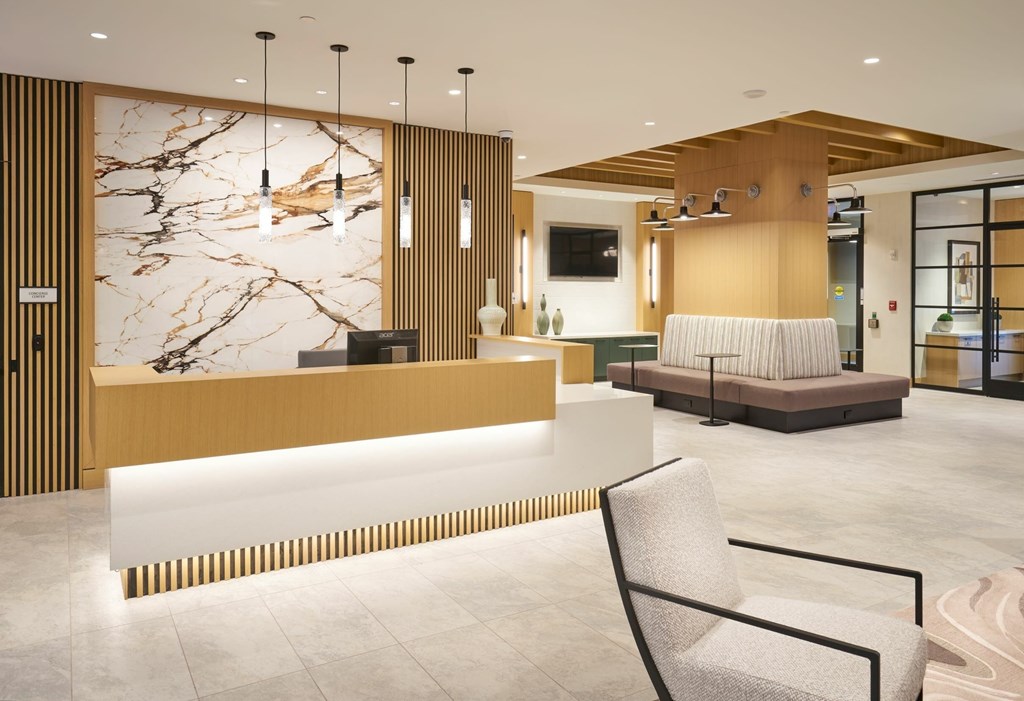 A reception area with a marble wall and a chair.