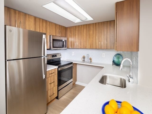 A kitchen with a stainless steel refrigerator, microwave, oven, and sink.