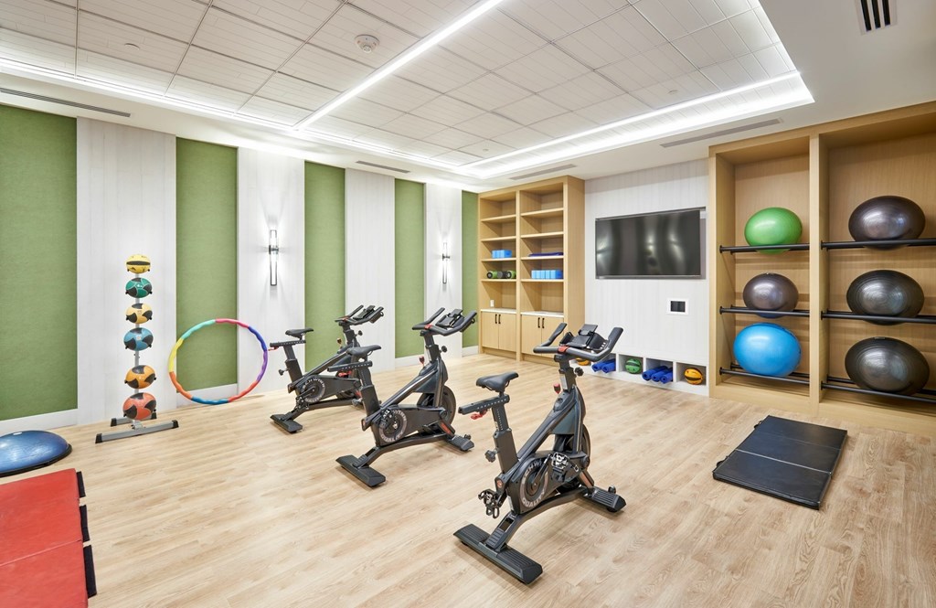 A gym with exercise equipment and a green wall.