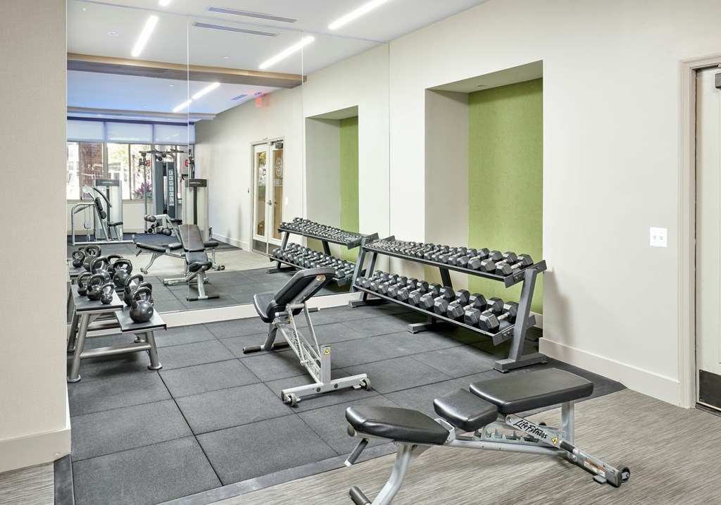 A gym with a variety of equipment including weights and weight machines.