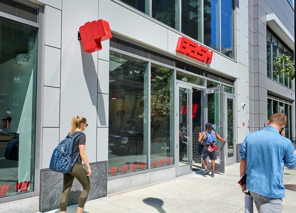A woman with a blue backpack is walking past a Bose store.