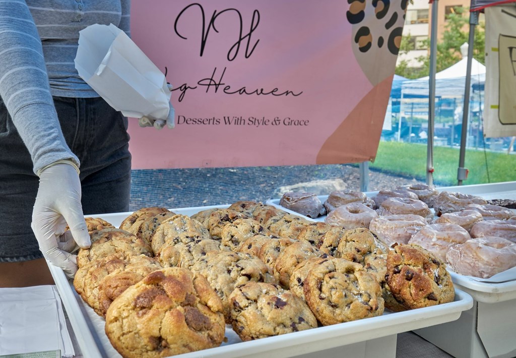 A person is serving scones from a tray at a bake sale.