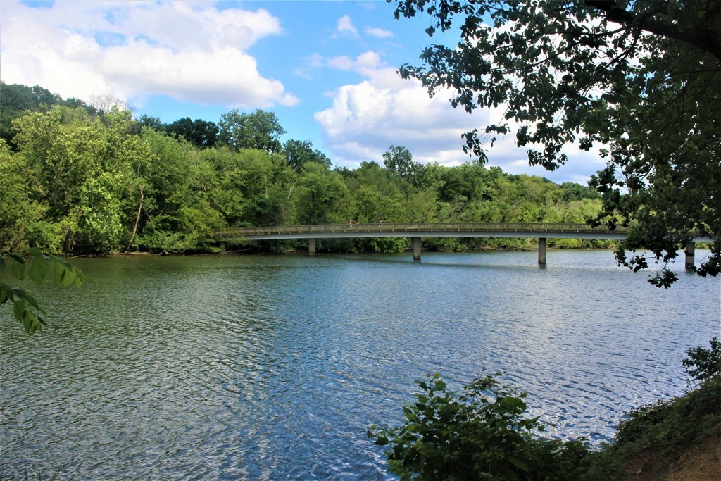 A serene lake surrounded by lush greenery under a clear blue sky.