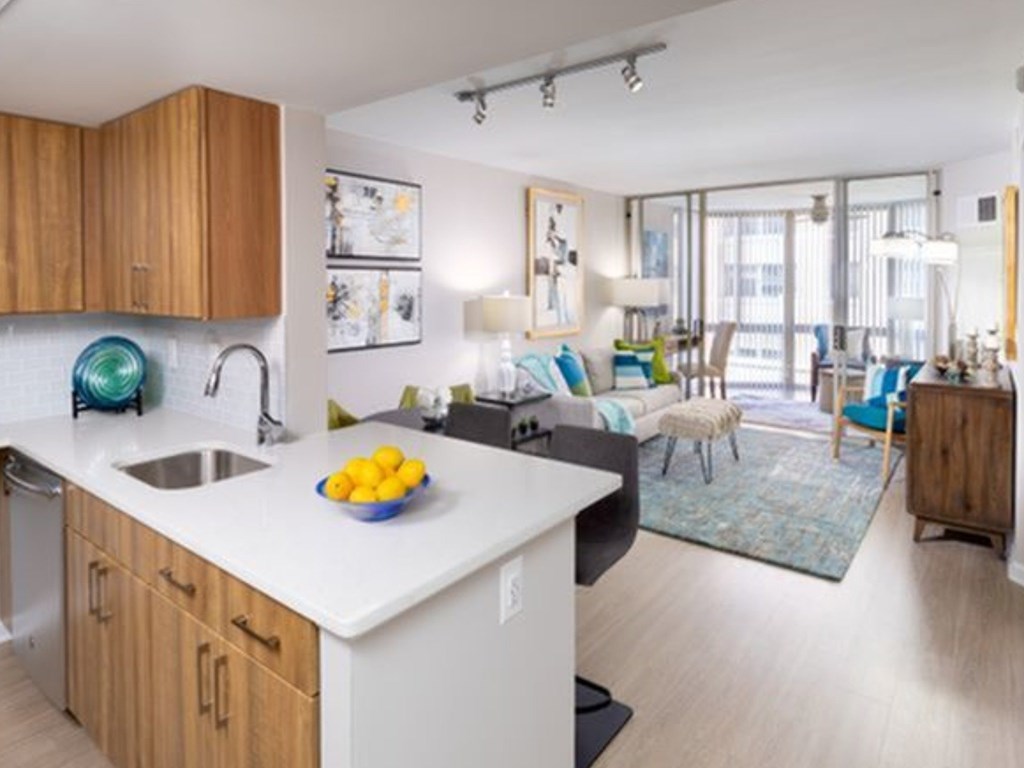A kitchen with a white counter top and wooden cabinets.