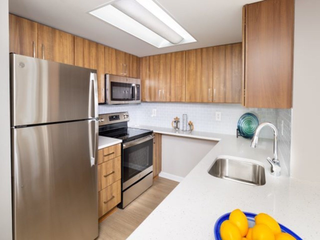 A kitchen with a stainless steel refrigerator, microwave, oven, and sink.