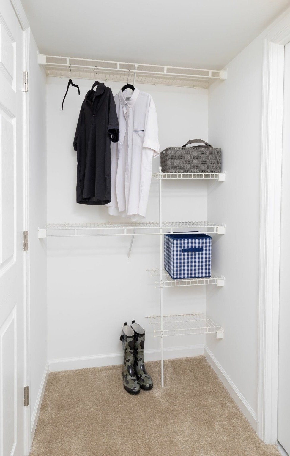 A white closet with a black robe hanging on a rod.