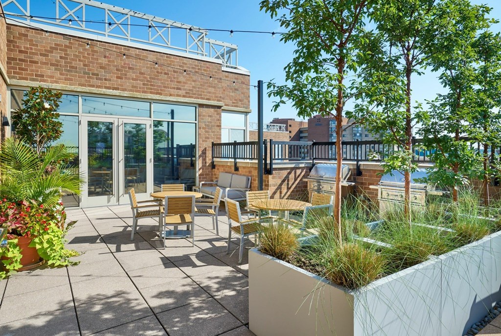 A patio with a table and chairs is surrounded by greenery.