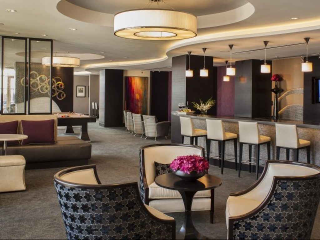 A modern lounge area with patterned chairs and a round table with a vase of flowers on it.