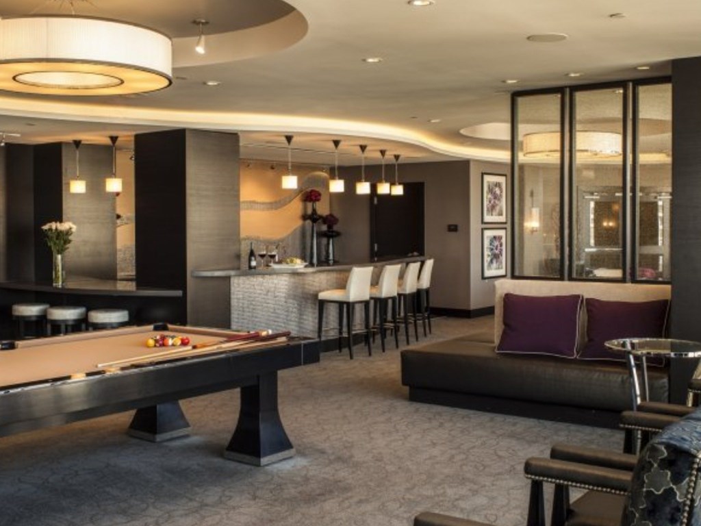 A billiard table is in the middle of a room with a couch and chairs.