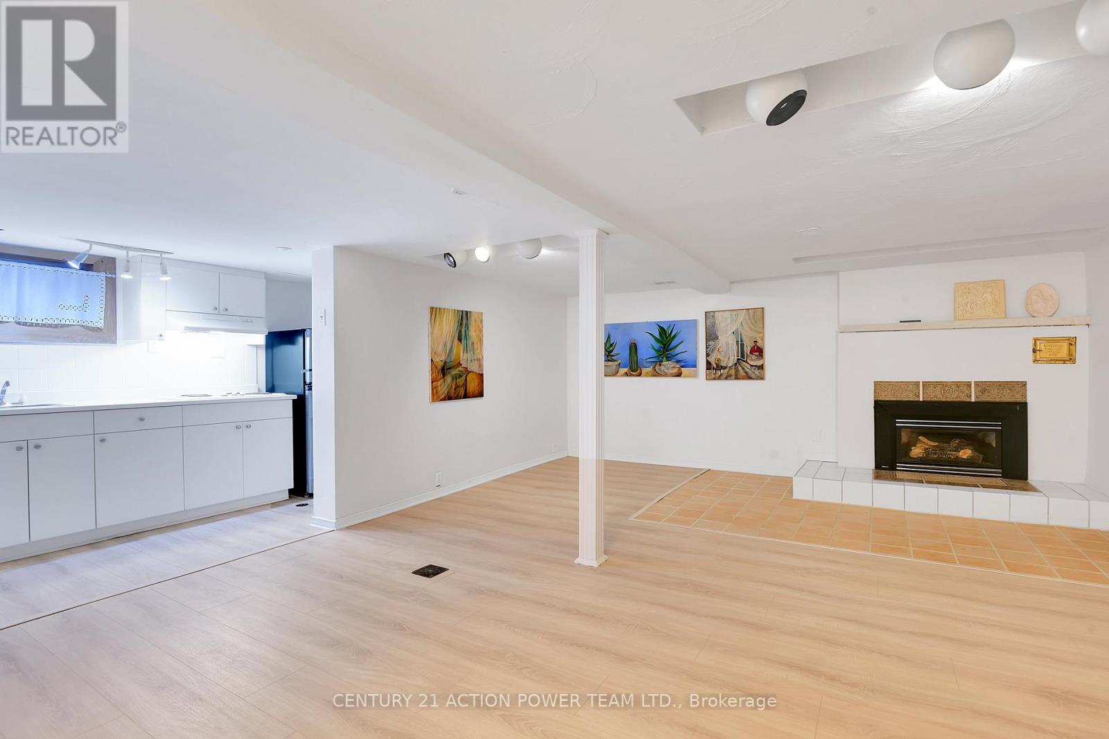 A spacious living room with a fireplace and a painting on the wall.