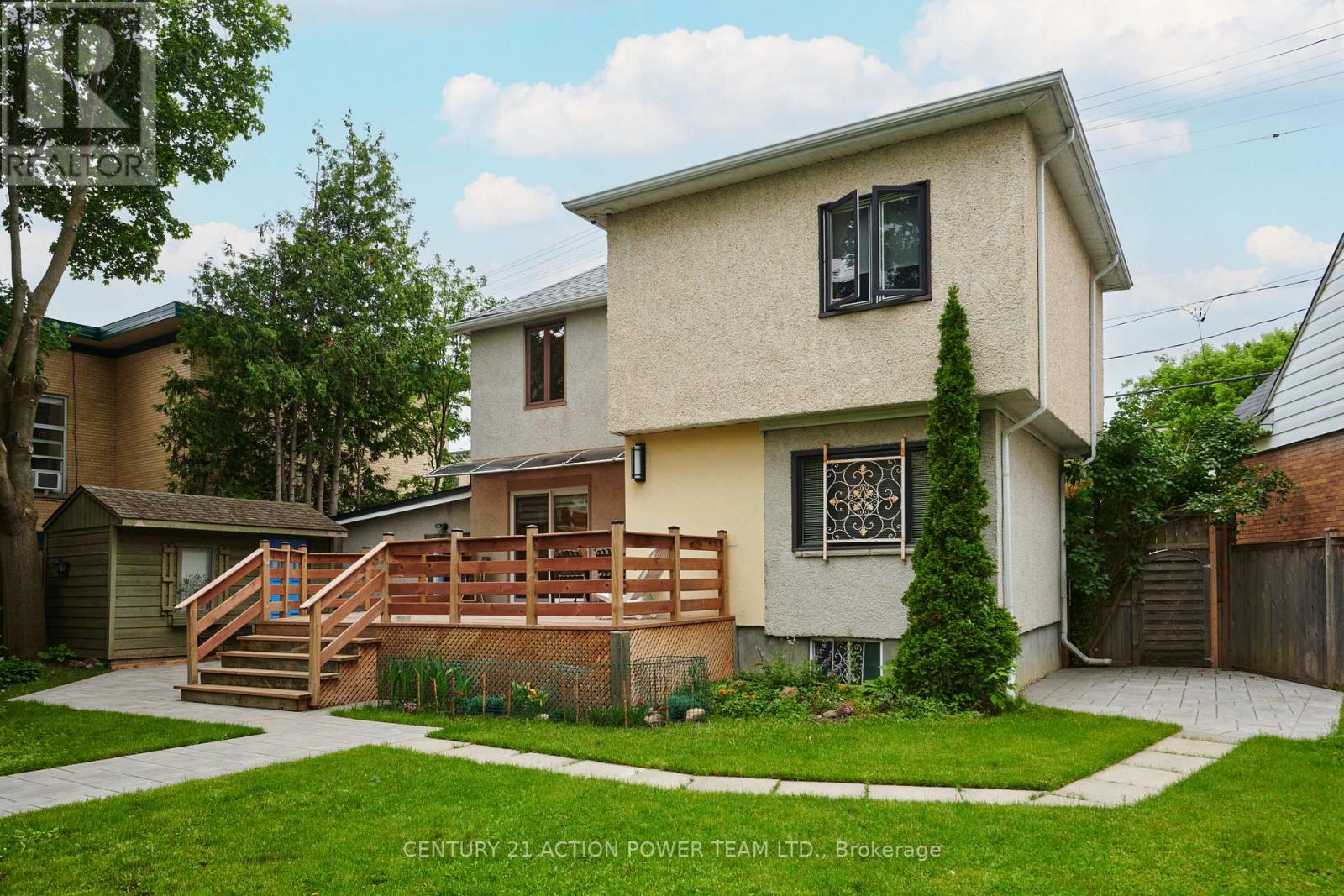 A house with a beige exterior and a deck in the front yard.