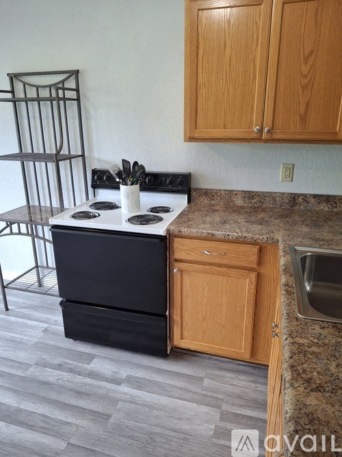 A kitchen with a black stove top oven and wooden cabinets.