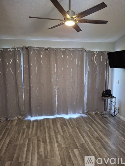 A room with a ceiling fan and a curtain.