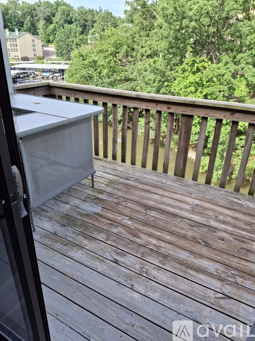 A wooden deck with a glass door leading to a balcony overlooking a wooded area.