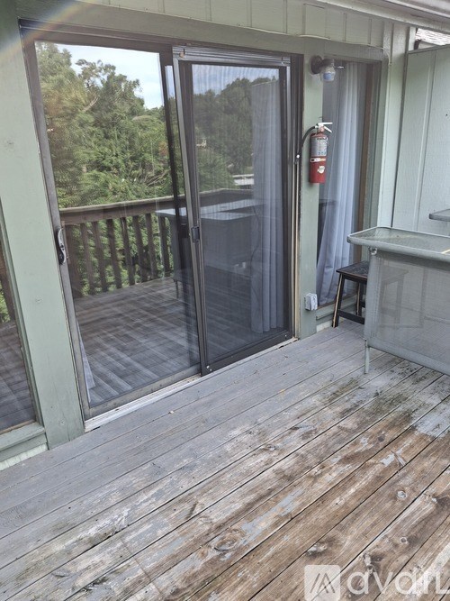A deck with a glass door leading to a balcony.