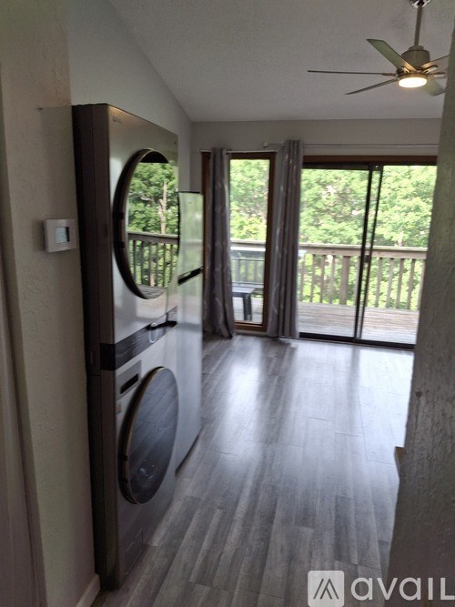 A laundry room with a washer and dryer, a ceiling fan, and sliding glass doors leading to a balcony.