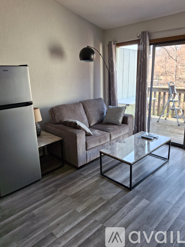 A living room with a grey couch and a glass coffee table.