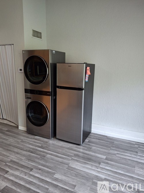 A stainless steel dishwasher and refrigerator in a room with wooden flooring.