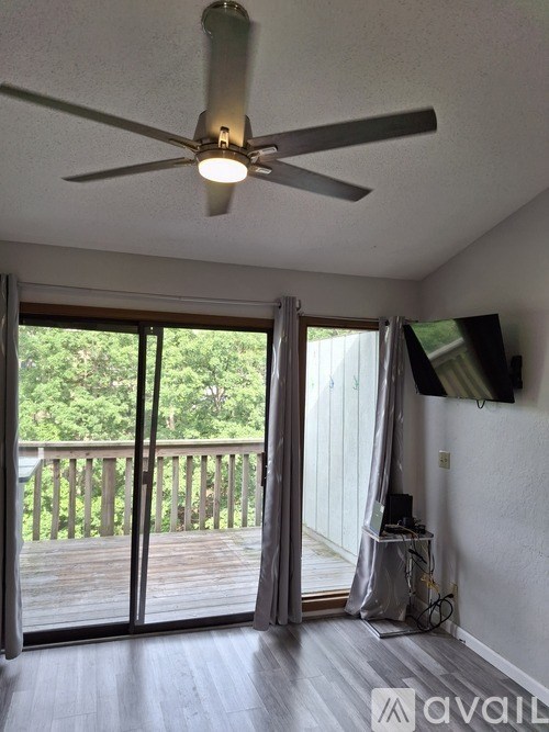 A room with a ceiling fan and sliding glass doors leading to a deck.