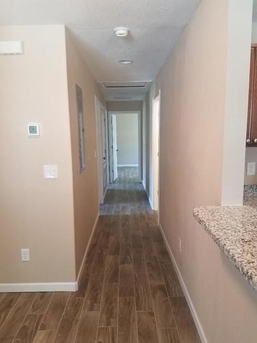 A long hallway with wood floors and white walls.