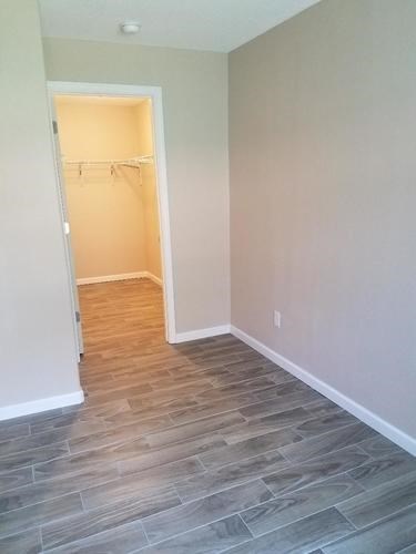 A room with a doorway leading to another room with a wooden floor.