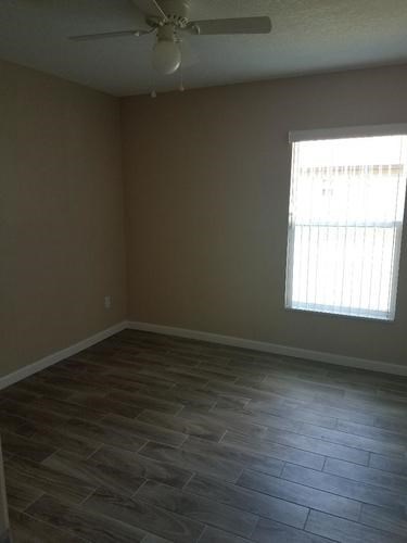 A room with a ceiling fan and a window with blinds.