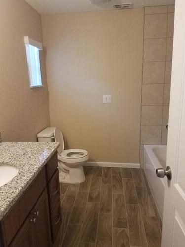 A bathroom with a toilet, sink, and wooden floors.