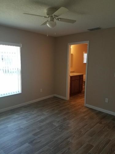 A room with a ceiling fan and a doorway leading to another room.