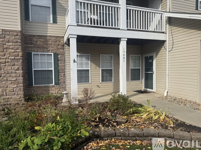 A balcony of a house with a brick wall and a white railing.