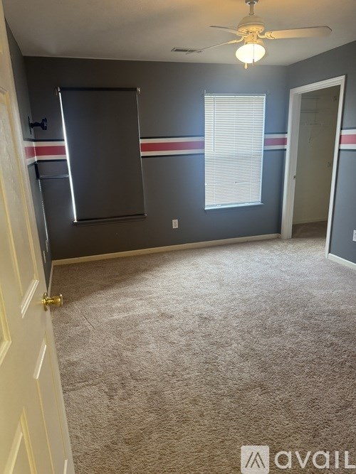 A room with a ceiling fan and a window with blinds.