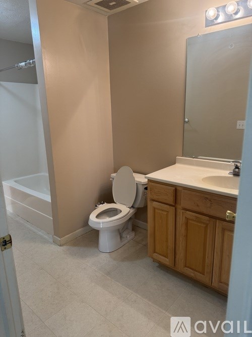 A bathroom with a toilet, sink, and mirror.