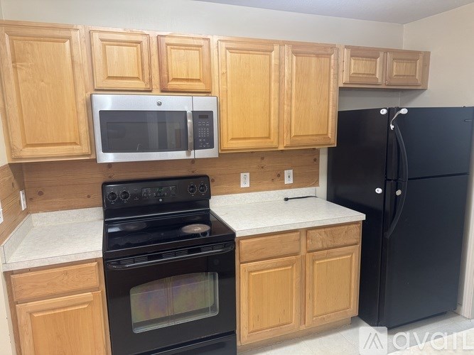 A kitchen with wooden cabinets and black appliances.