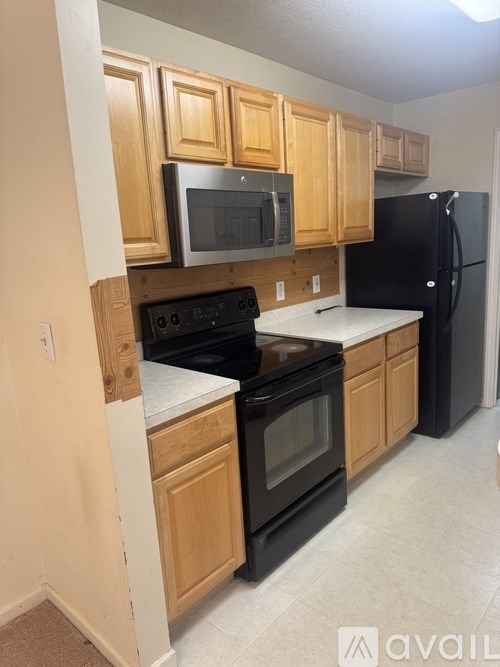 A kitchen with wooden cabinets and black appliances.