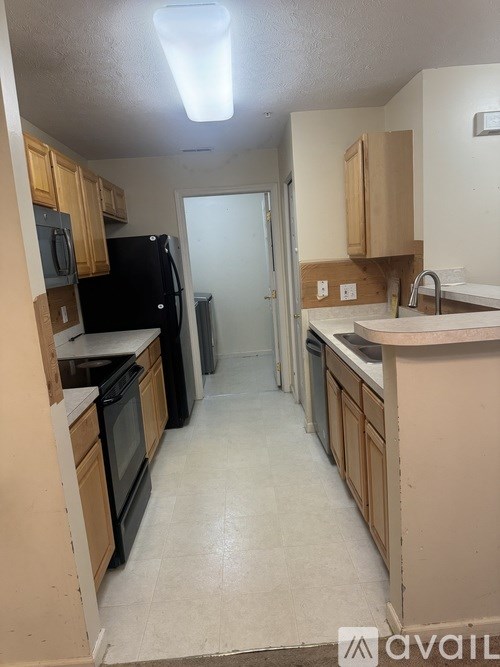A kitchen with black appliances and wooden cabinets.