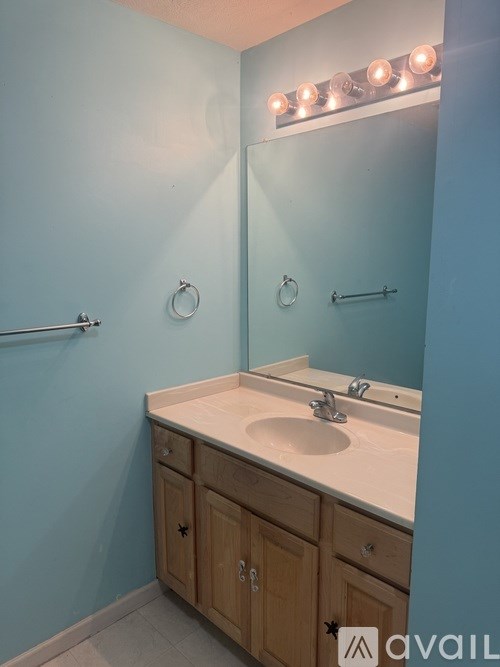 A bathroom with a sink and a mirror with lights above it.