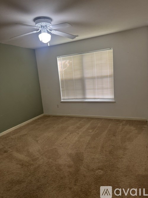 A room with a ceiling fan and a window with blinds.