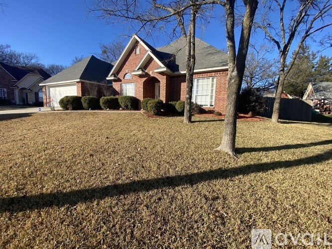 A house with a red brick exterior and a large lawn in front.