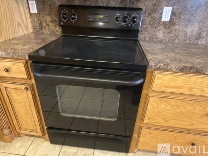 A black oven with a digital display is installed in a kitchen with wooden cabinets.