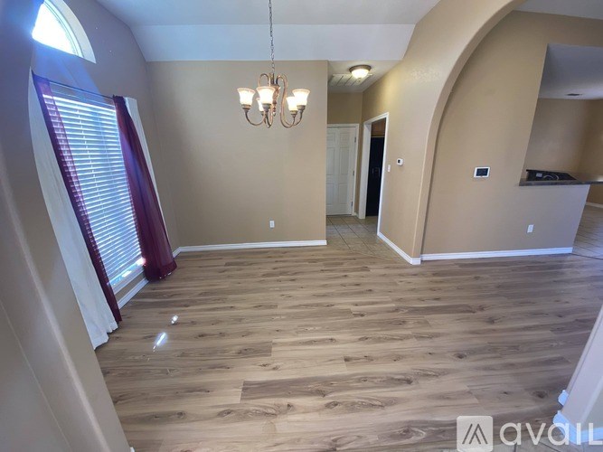 A spacious room with wooden flooring and a chandelier.