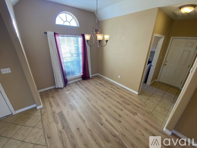 A room with wooden flooring and a window with curtains.