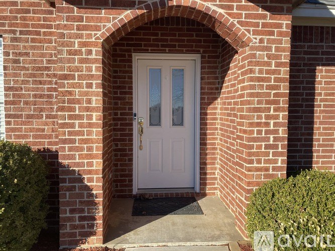 A white door is set in a brick archway.