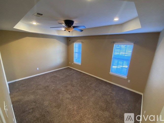 A room with a ceiling fan and carpeted floor.