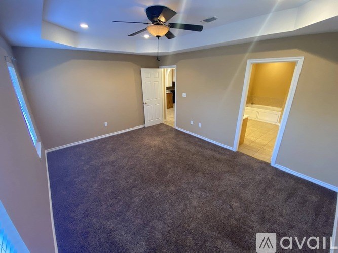 A room with a ceiling fan and carpeted floor.